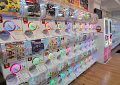 A store aisle lined with illuminated capsule-toy machines
